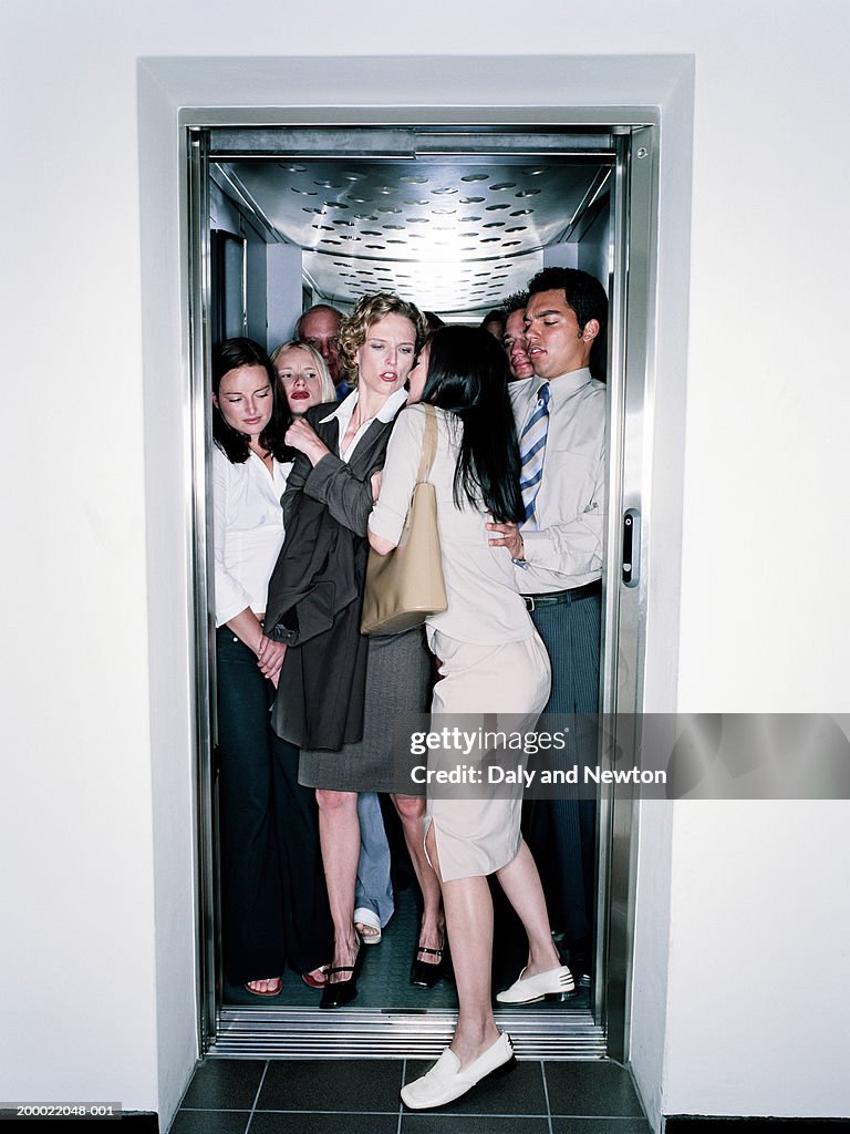 Young woman squeezing into crowded lift