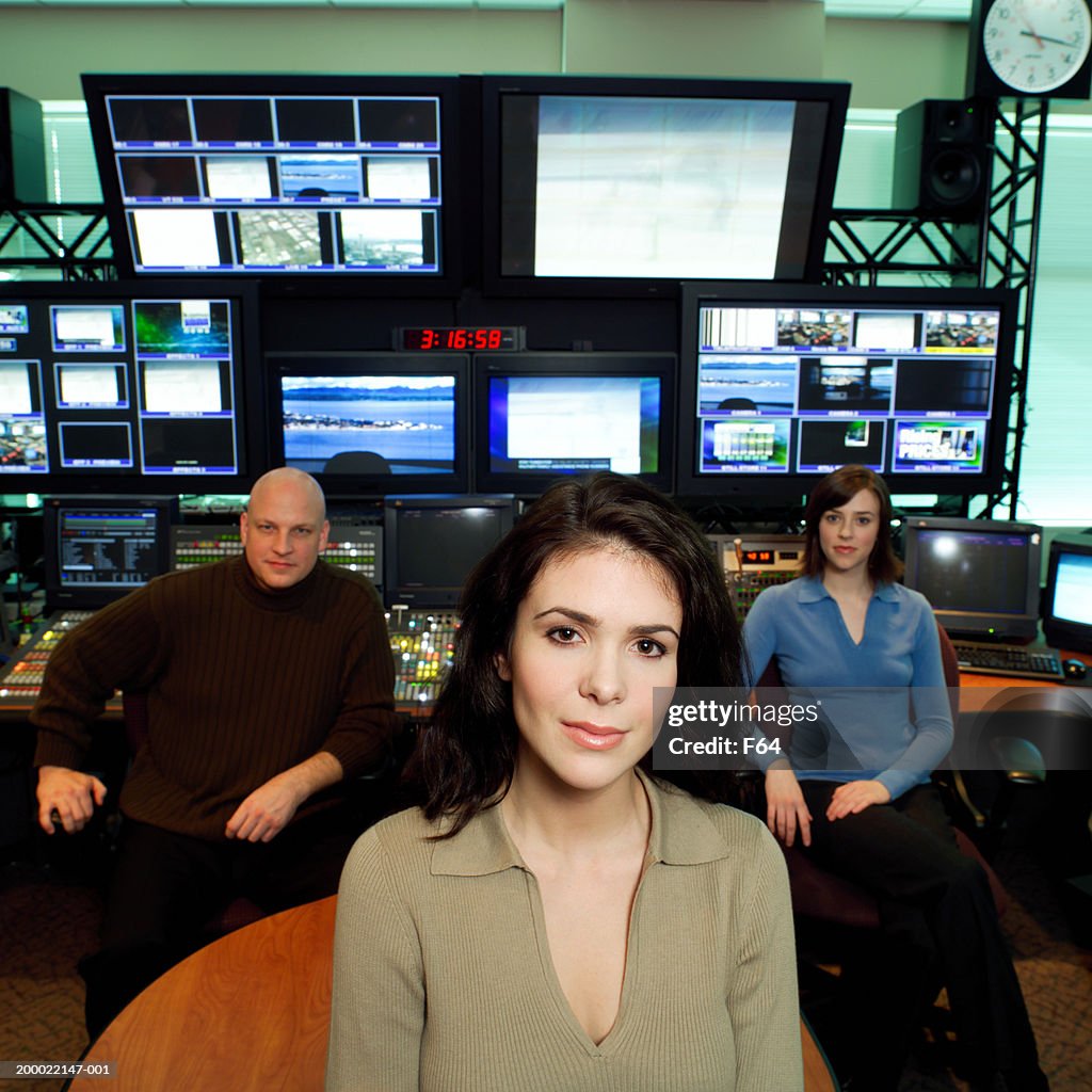 Three people seated in television control room