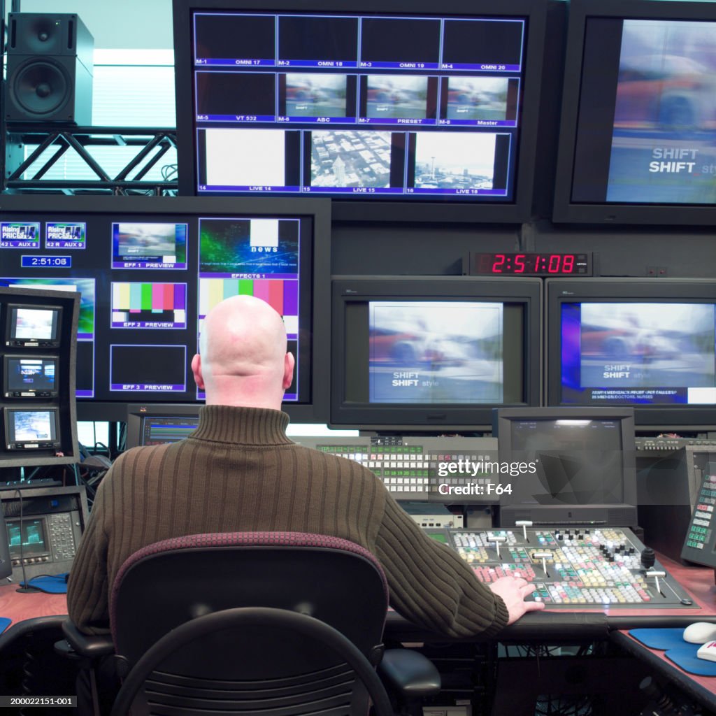 Man working in television studio control room, rear view