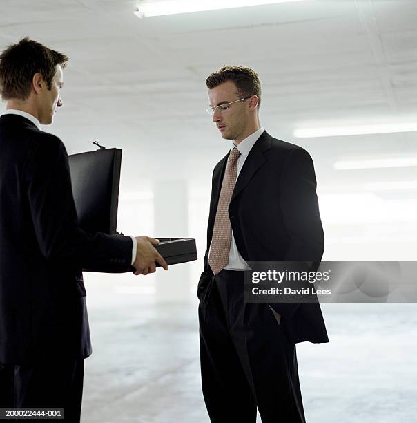 businessman holding open briefcase in front of colleague - corruption stock pictures, royalty-free photos & images