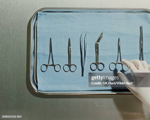 gloved hand reaching for surgical scissors on metal tray - 外科用ハサミ ストックフォトと画像