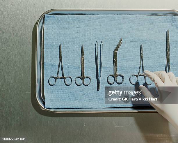 gloved hand reaching for surgical scissors on metal tray - equipamento cirúrgico imagens e fotografias de stock
