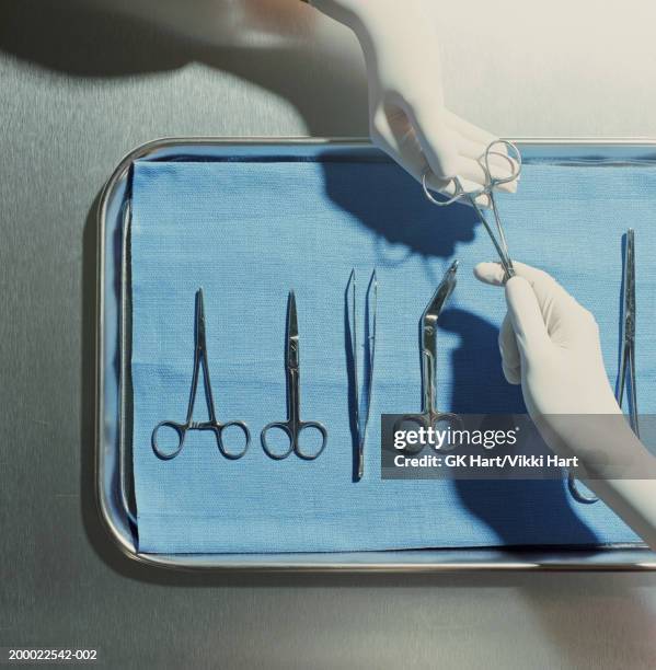 gloved hands passing surgical scissors - surgery tools stock pictures, royalty-free photos & images