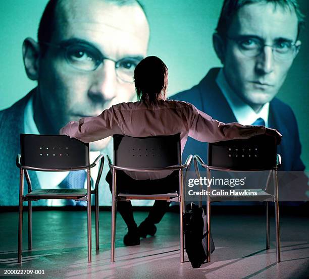 man watching projection of two businessmen, rear view - conference large screen foto e immagini stock