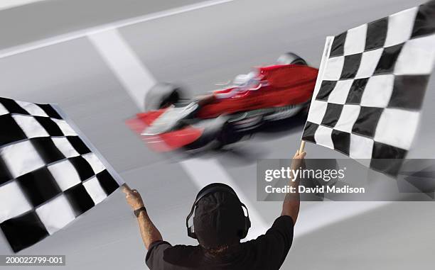 official waving checkered flags at car crossing finish line - geblokte vlag stockfoto's en -beelden