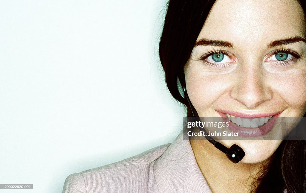 Young woman wearing telephone headset, smiling, portrait, close-up