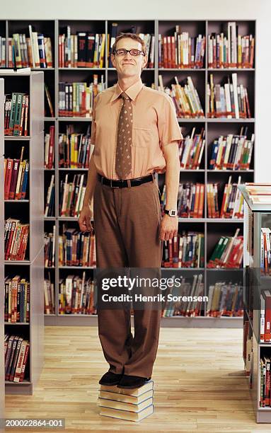 man standing on books in library, portrait - nerd stock pictures, royalty-free photos & images