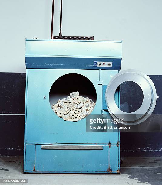 wads of bank notes in industrial washing machine - money laundering foto e immagini stock