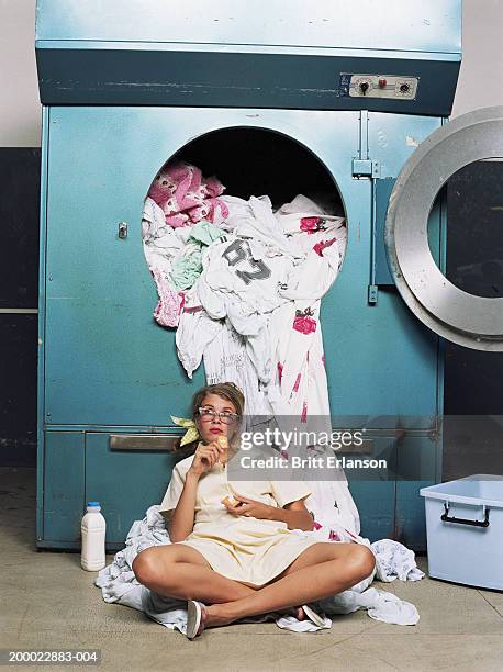 teenage girl (16-18) taking break beside industrial washing machine - perder el tiempo fotografías e imágenes de stock