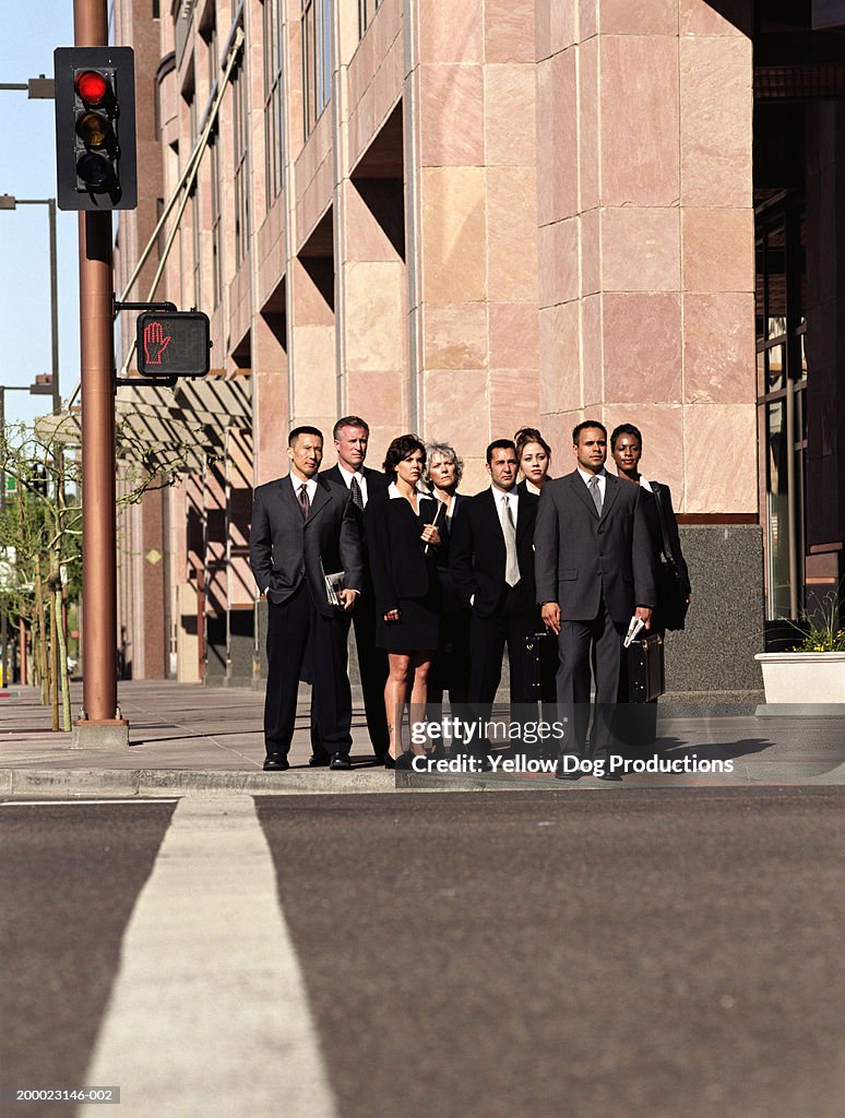 Businesspeople on curb waiting to cross street