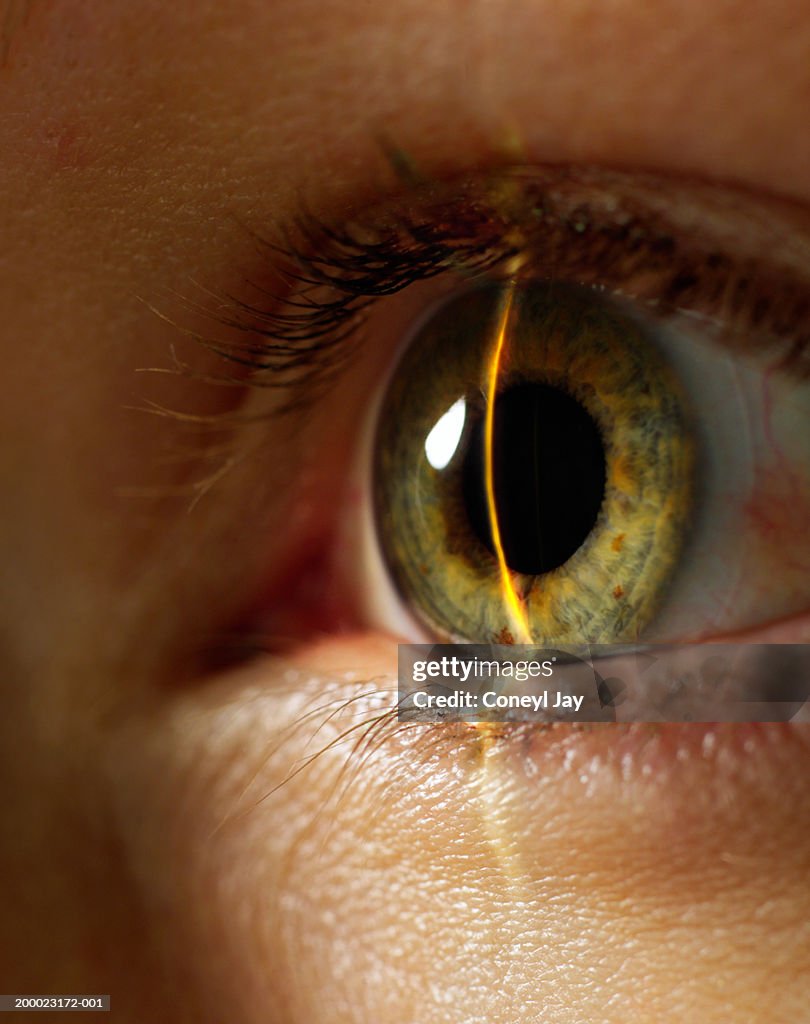 Beam of light shining on woman's eye, close-up