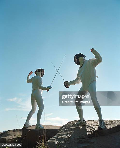 man and woman fencing, standing on flat rocks - mask confrontation stock pictures, royalty-free photos & images