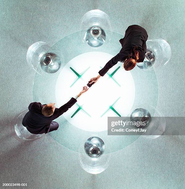 two business people reaching across glass table, overhead view - overdracht business mensen stockfoto's en -beelden