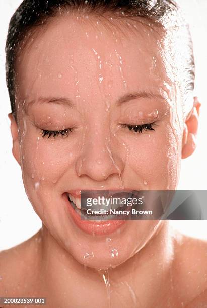 young woman with water dripping down face, smiling, close-up - face down stock-fotos und bilder