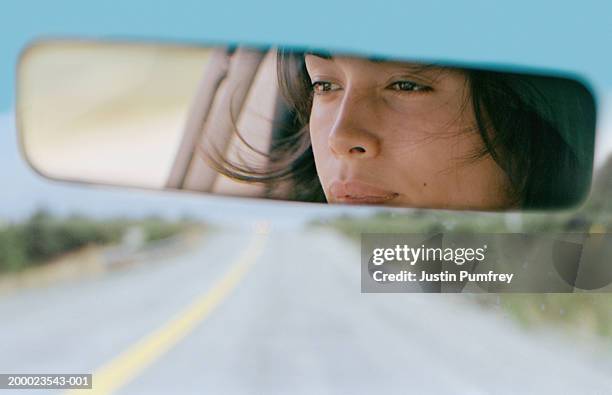 woman driving car reflected in rear view mirror, close-up - fahrzeugspiegel stock-fotos und bilder