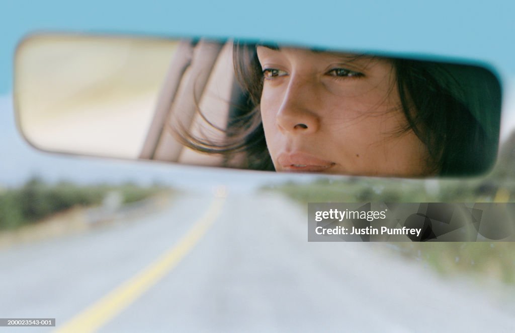 Woman driving car reflected in rear view mirror, close-up