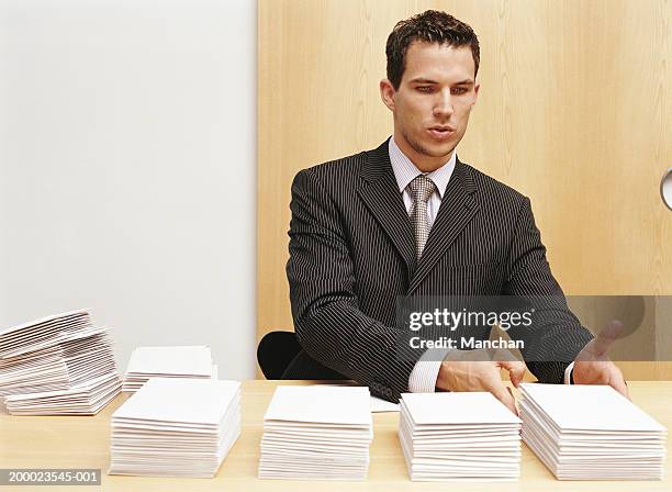 young businessman stacking envelopes on desk - obsessive stockfoto's en -beelden