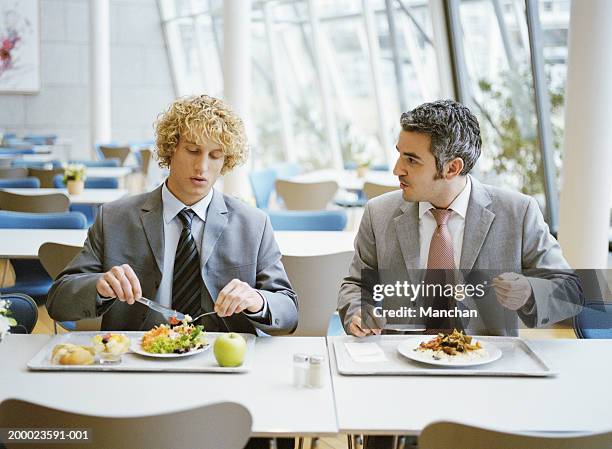 two male business colleagues in canteen having lunch - pausa pranzo foto e immagini stock