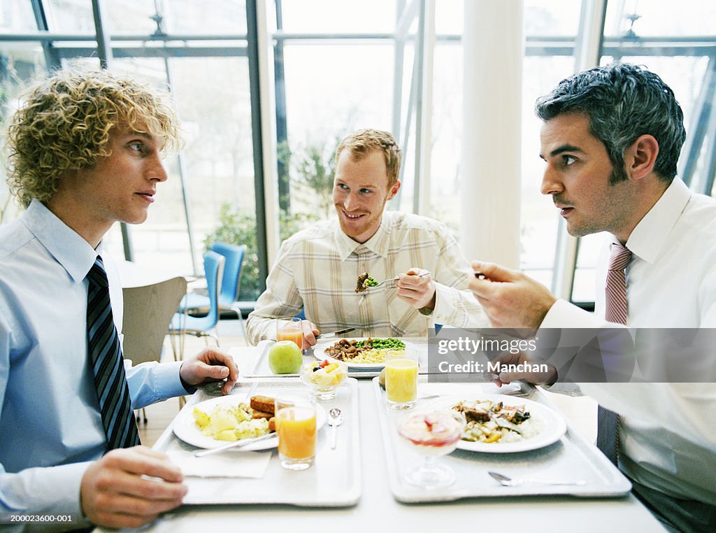 Three business colleagues in canteen having lunch, close-up