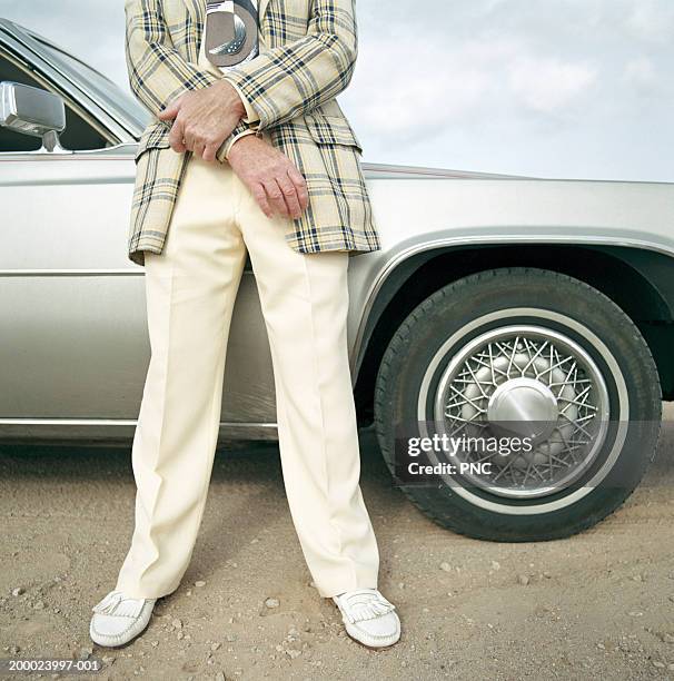 man in suit leaning against car, low section - cheesy salesman stockfoto's en -beelden