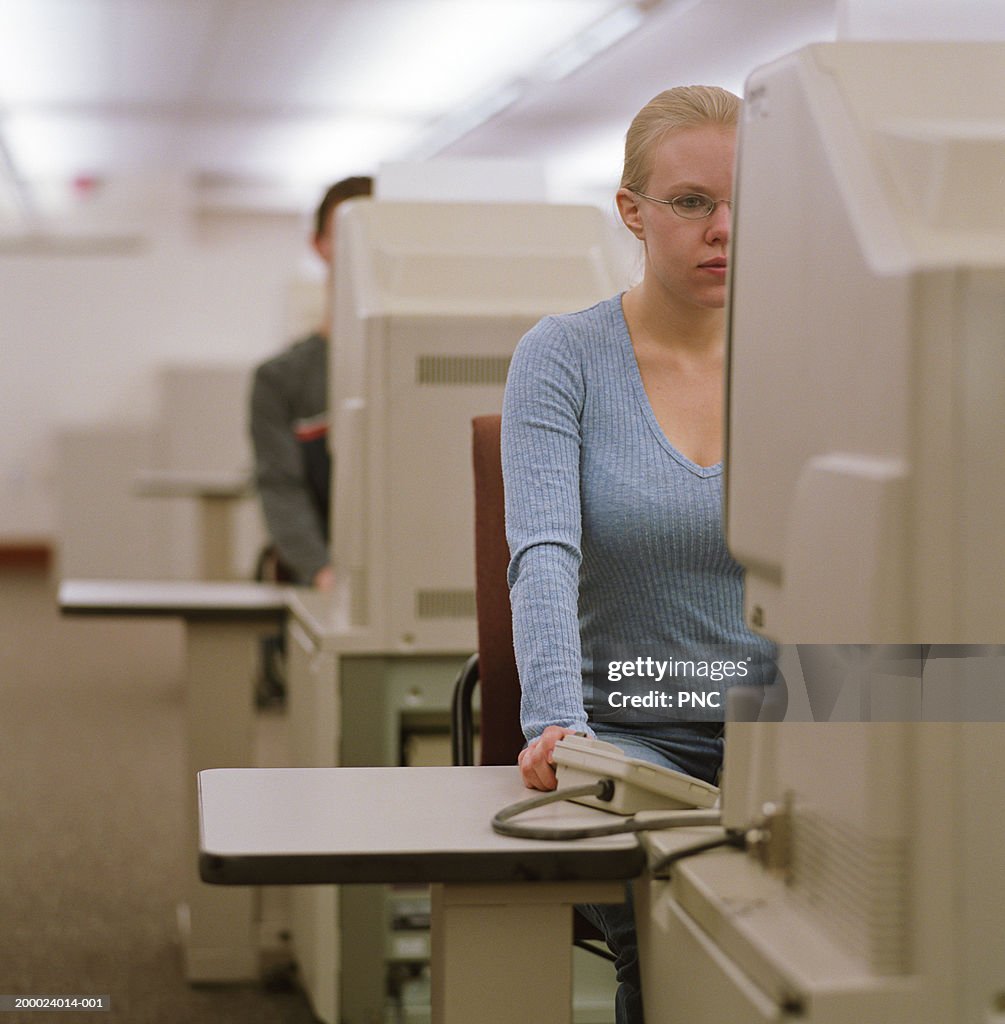 College student using microfilm machine in library