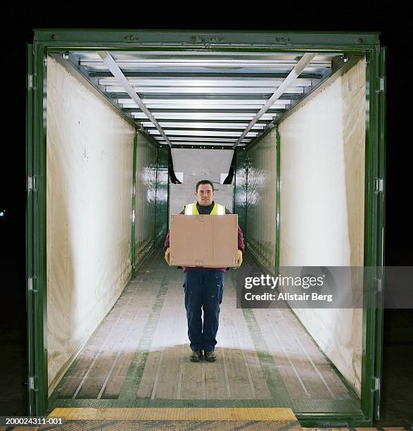 man in back of lorry holding cardboard box, portrait - dump truck stock-fotos und bilder