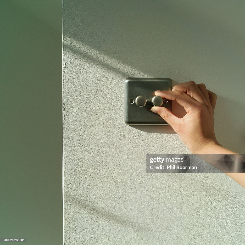 Young woman adjusting dimmer switch, close-up