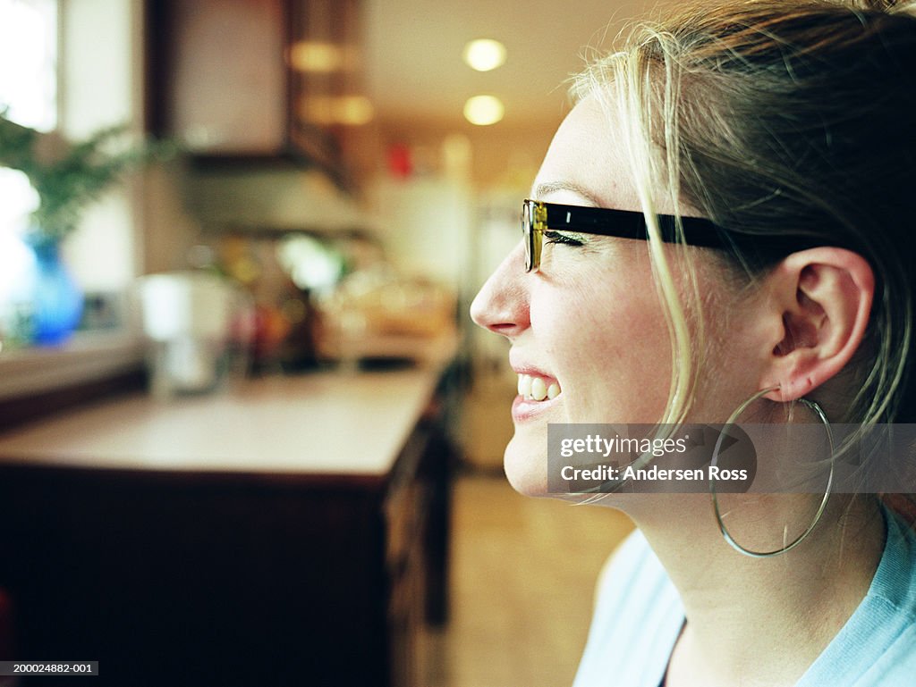 Young woman sitting in kitchen, profile, close-up