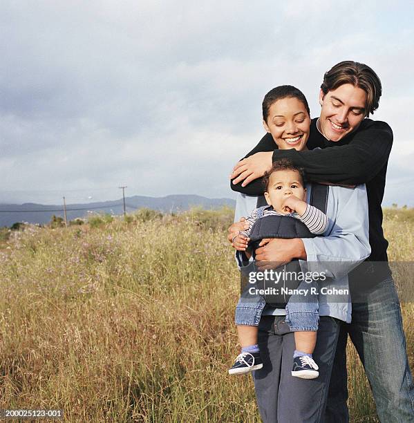 mother and father with baby boy (6-9 months) in baby carrier - baby carrier stock pictures, royalty-free photos & images