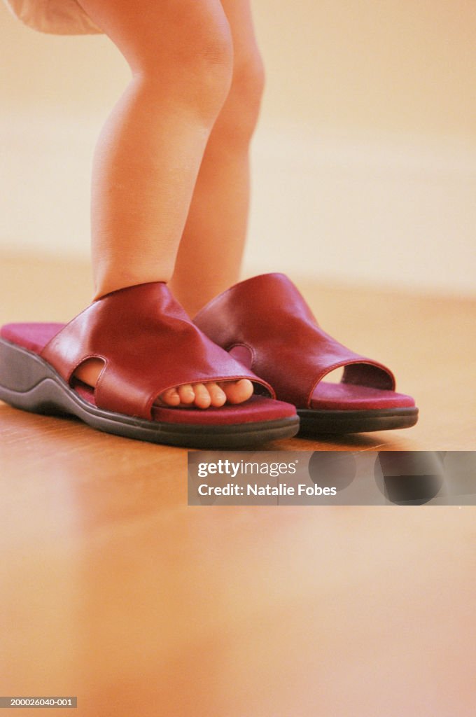 Girl (21-24 months) walking in Mom's sandals, low section