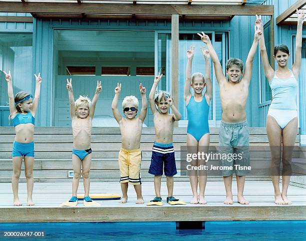 group of children (3-15) in swimwear, arms raised in victory sign - swimming trunks stock pictures, royalty-free photos & images
