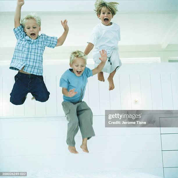 three boys (4-6) jumping, indoors - jump on bed photos et images de collection