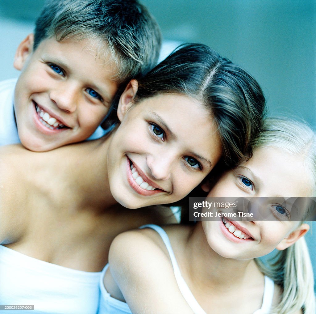 Three smiling children (8-15), heads together, portrait, close-up