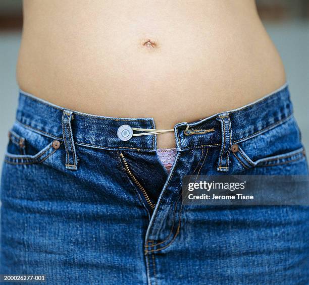 young woman, jeans held together with elastic band, mid section - elastiekje stockfoto's en -beelden