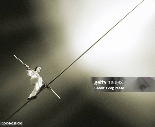 performer walking tightrope, low angle view (grainy, infrared b&w) - tight rope imagens e fotografias de stock