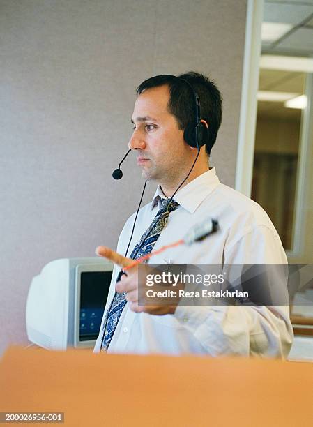 businessman wearing headset, standing in office, twirling key chain - stoneplus1 stock pictures, royalty-free photos & images