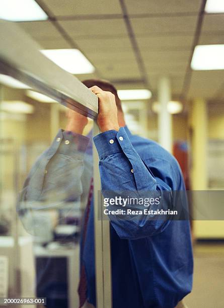 businessman leaning on glass partition in office, side view - stoneplus1 stock pictures, royalty-free photos & images
