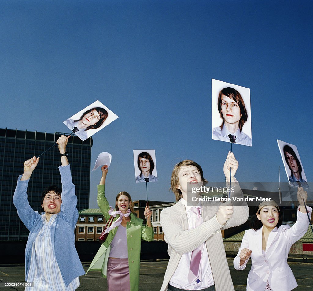 Four people holding up placards bearing identical image of man