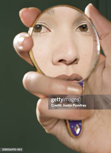 reflection of young woman looking in hand held mirror, portrait - espejo fotografías e imágenes de stock