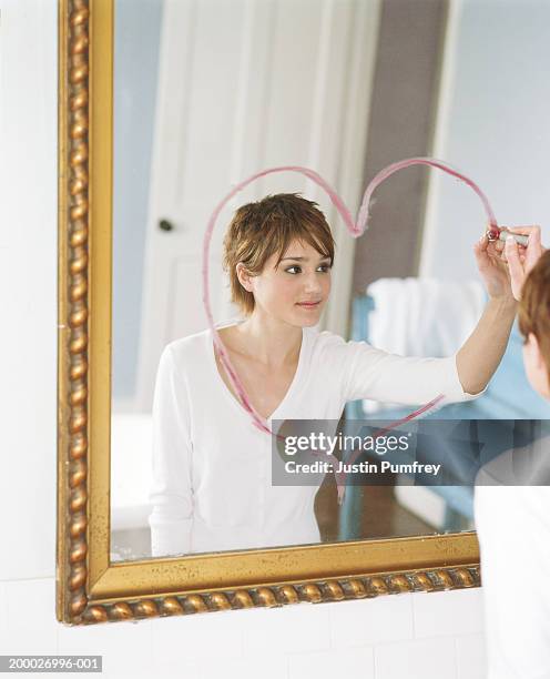 reflection of woman using lipstick to draw heart on mirror - lipstick heart stock pictures, royalty-free photos & images