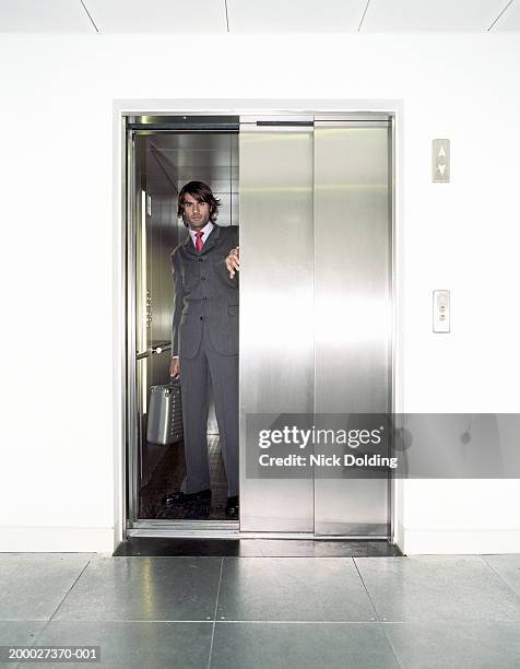 young businessman in lift, portrait, view through open door - elevator door stock pictures, royalty-free photos & images