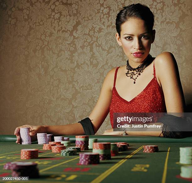 young woman at casino table holding pile of gambling chips, portrait - casino interior photos et images de collection