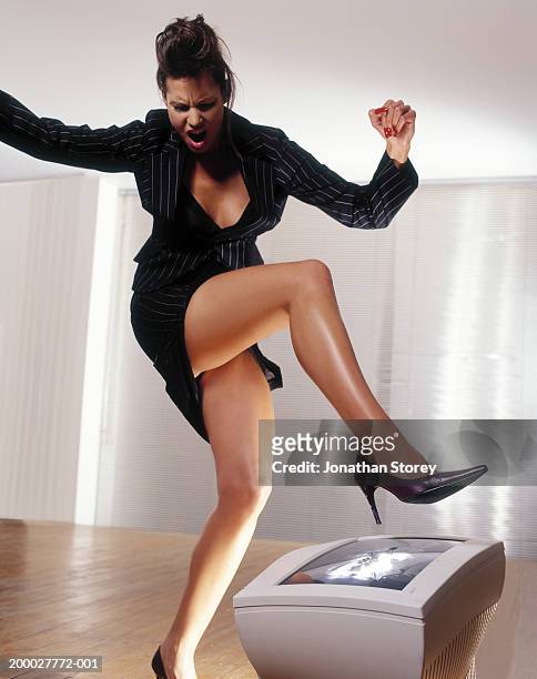 young businesswoman stamping on computer screen with stilletto heel - women wearing short skirts stockfoto's en -beelden