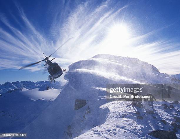 group of skiers on mountain top with helicopter - heli skiing stock pictures, royalty-free photos & images