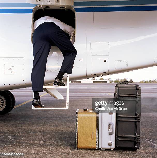 pilot loading luggage onto corporate jet, rear view - tomato_response stock pictures, royalty-free photos & images