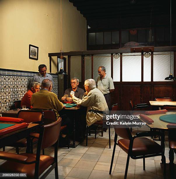 group of mature men playing cards in bar - card game mature people stock-fotos und bilder