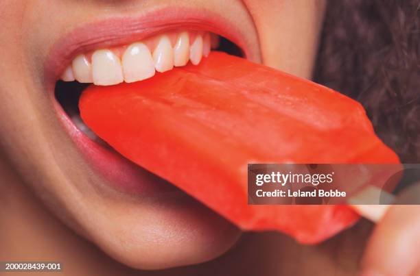 young woman eating popsicle, close up - stieleis stock-fotos und bilder