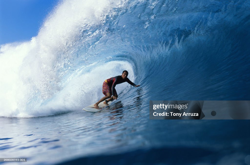 Young male surfer riding pipeline wave