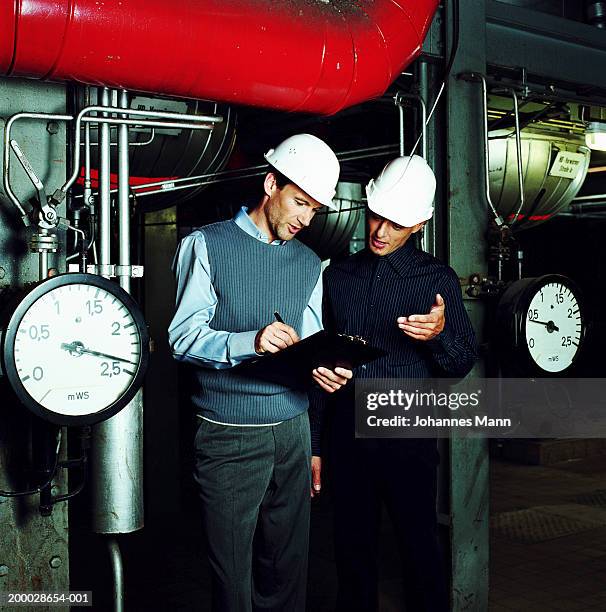 two workmen looking at clipboard in power station - pressure gauge stock pictures, royalty-free photos & images
