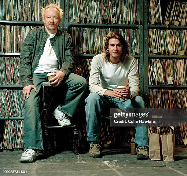 mature man and young man sitting by shelves of vinyl records, portrait - plattenladen stock-fotos und bilder